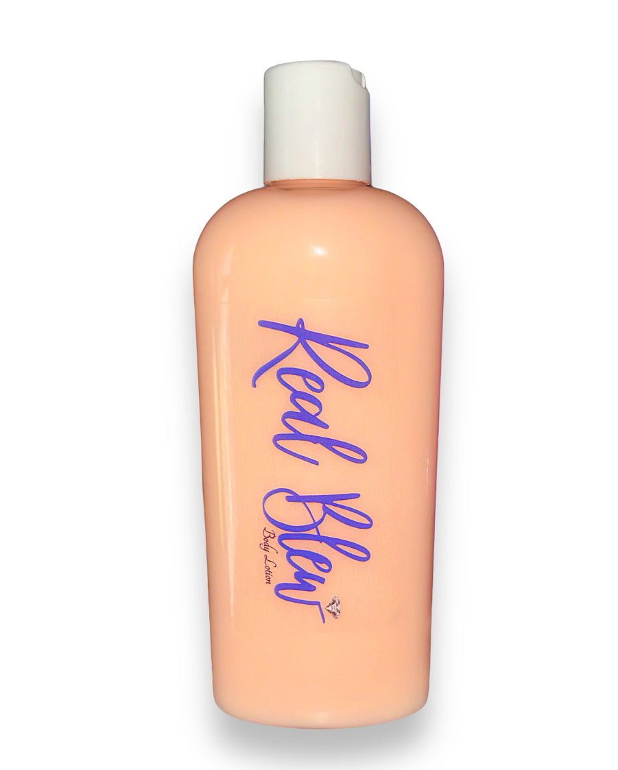 The image features a peach-colored body lotion in a clear plastic bottle with a white cap, labeled “Real Blew” in stylized cursive blue font. There’s also a small signature at the bottom right of the bottle underneath Real Blew labeled as "body lotion" The product is a peach scented body lotion🍑🧴